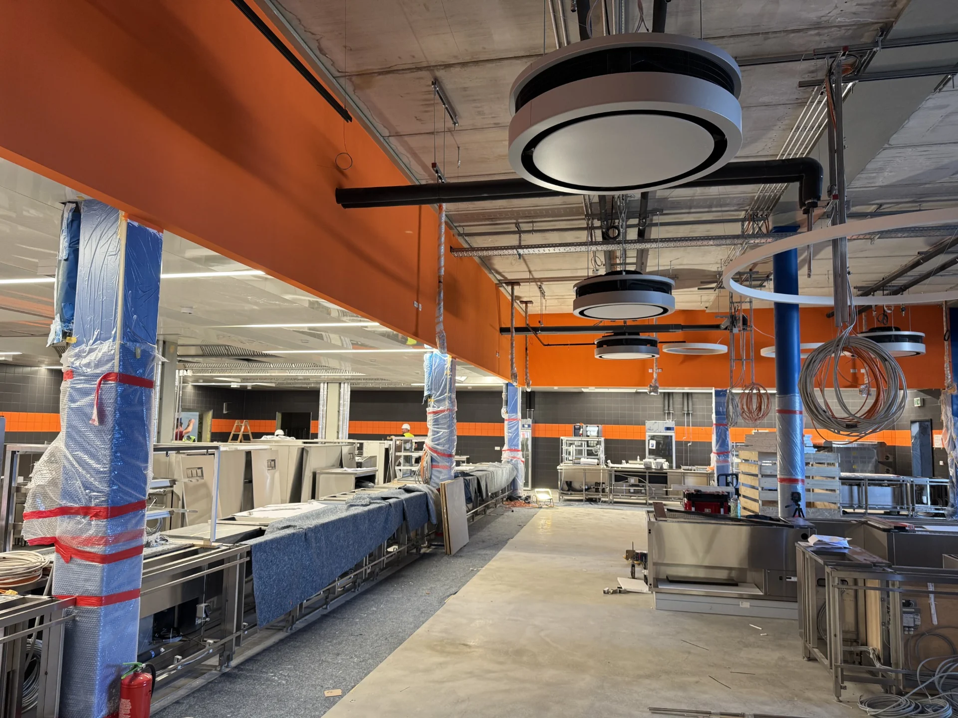 Gewerblicher Innenausbau mit orangefarbenen Deckenbereichen und geschützten Arbeitszonen