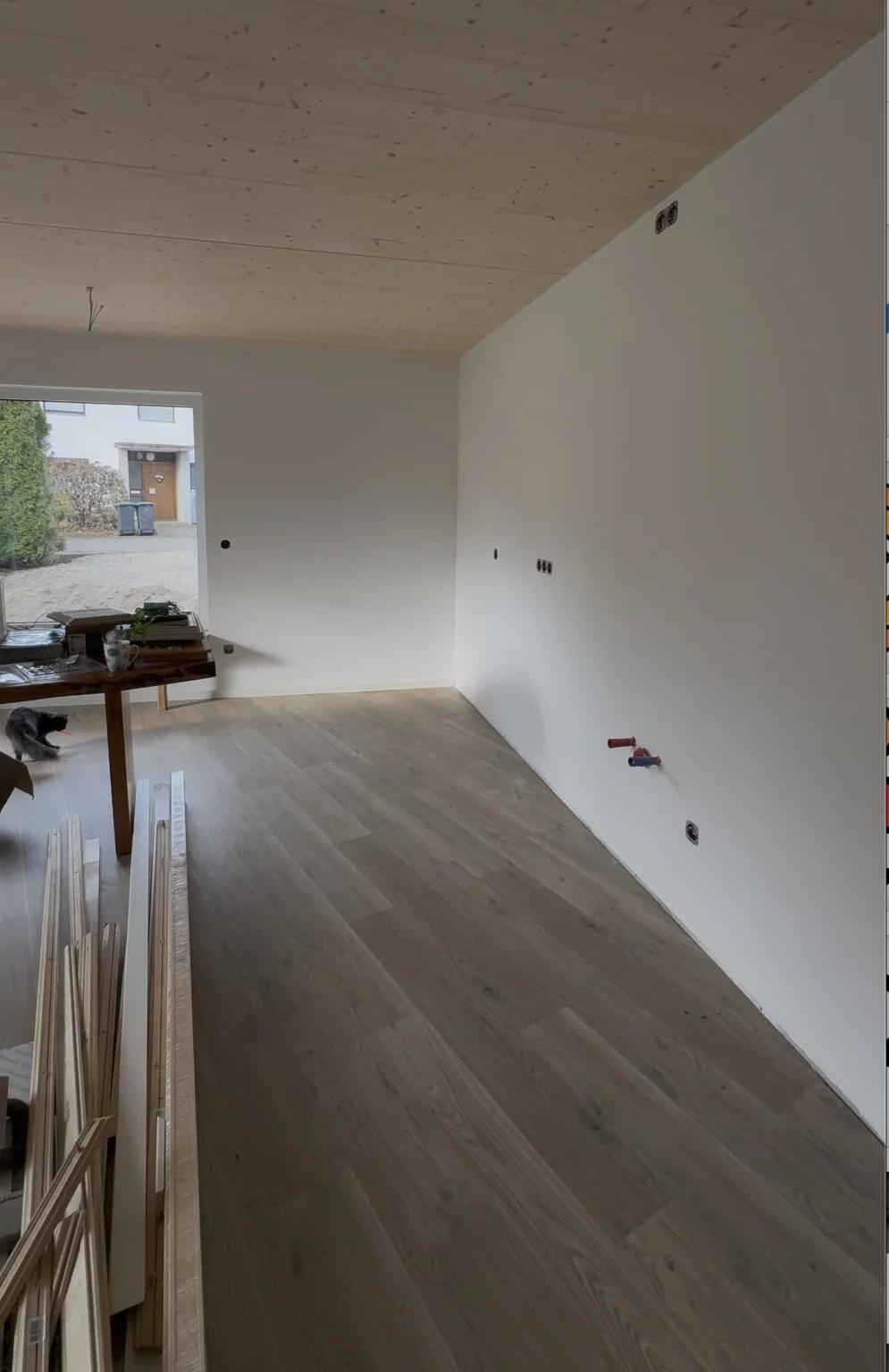 Innenausbau mit weißen Wandflächen, sichtbarer Holzdecke und Holzfußboden