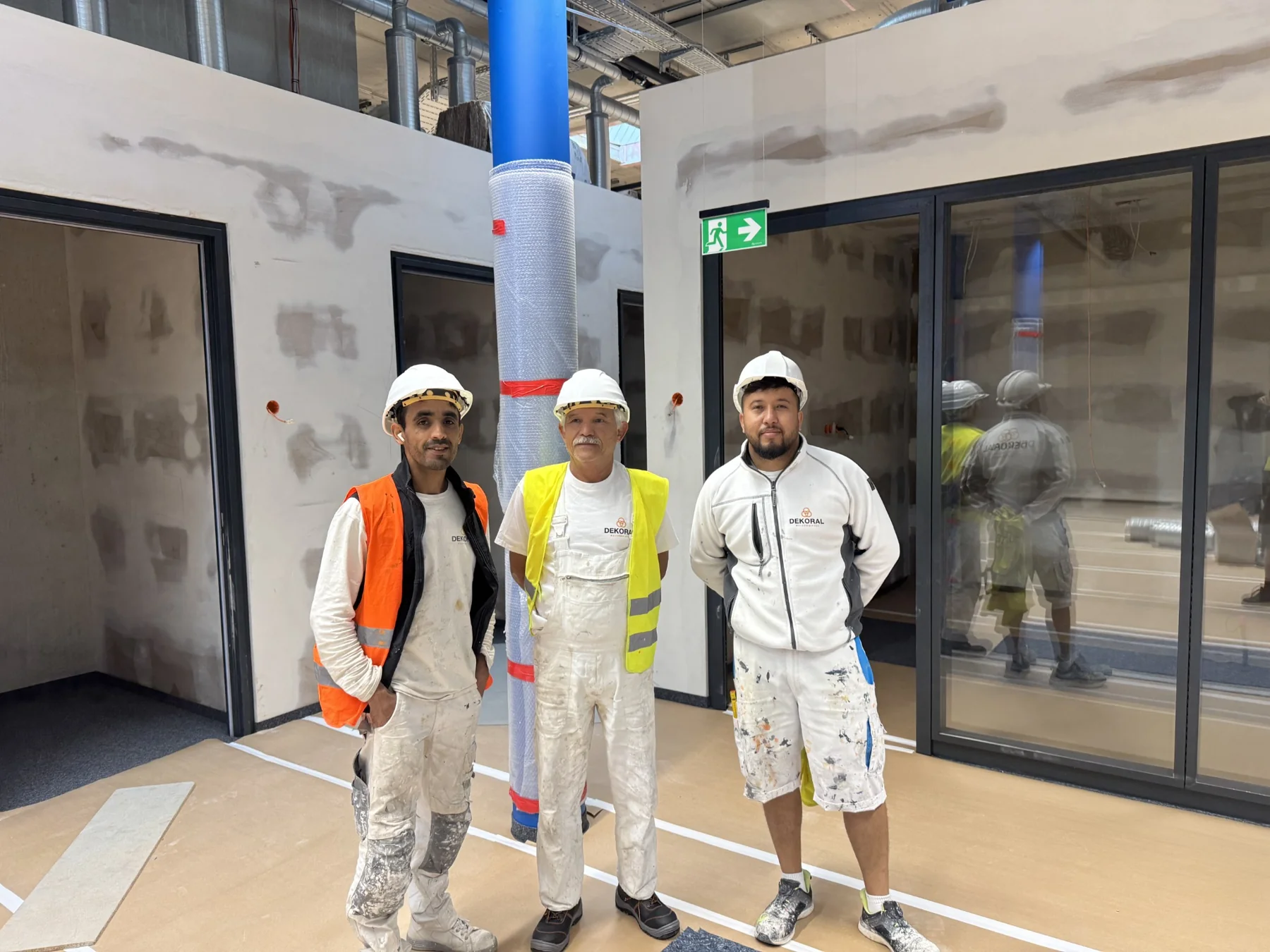 Drei Mitarbeiter des Dekoral-Teams in Arbeitskleidung auf einer Baustelle