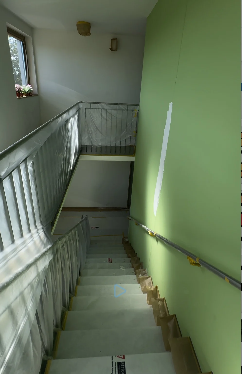 Grünes Treppenhaus mit vorbereiteten Wandflächen und abgedecktem Geländer